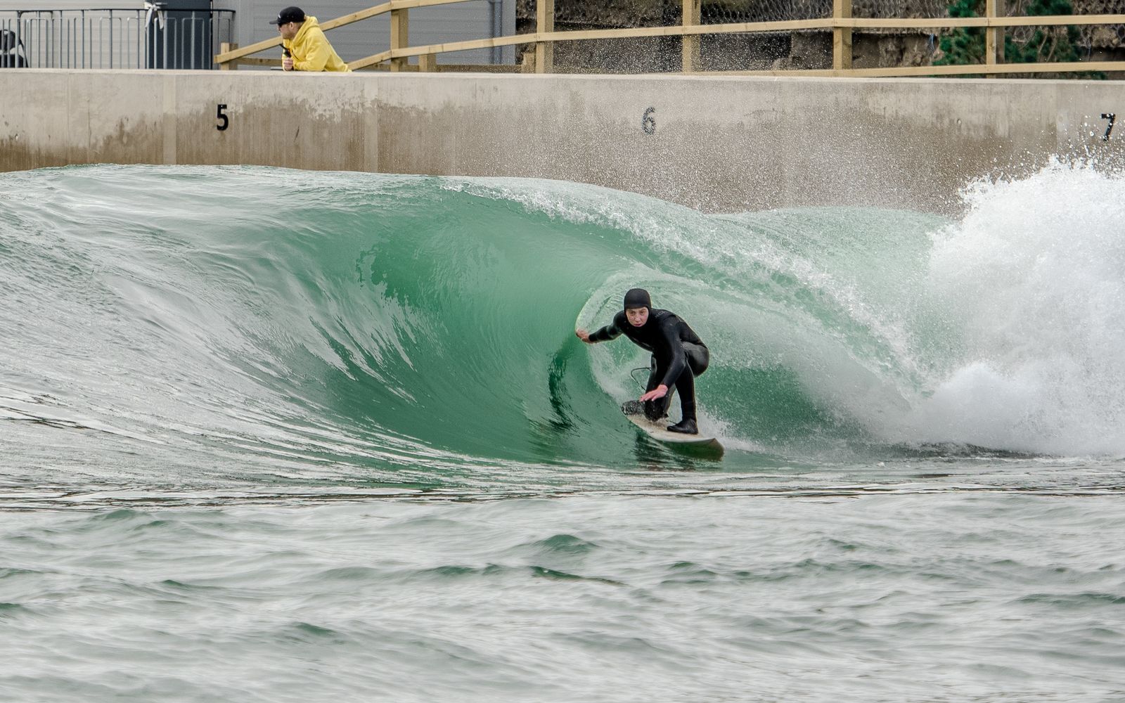 A surfer in a winter hood rides the barrel on the Barrels setting at Lost Shore.