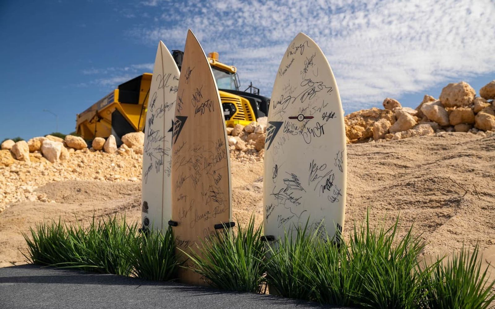 Signed surfboards and an excavator on the Jandakot site as construction began in April 2026.