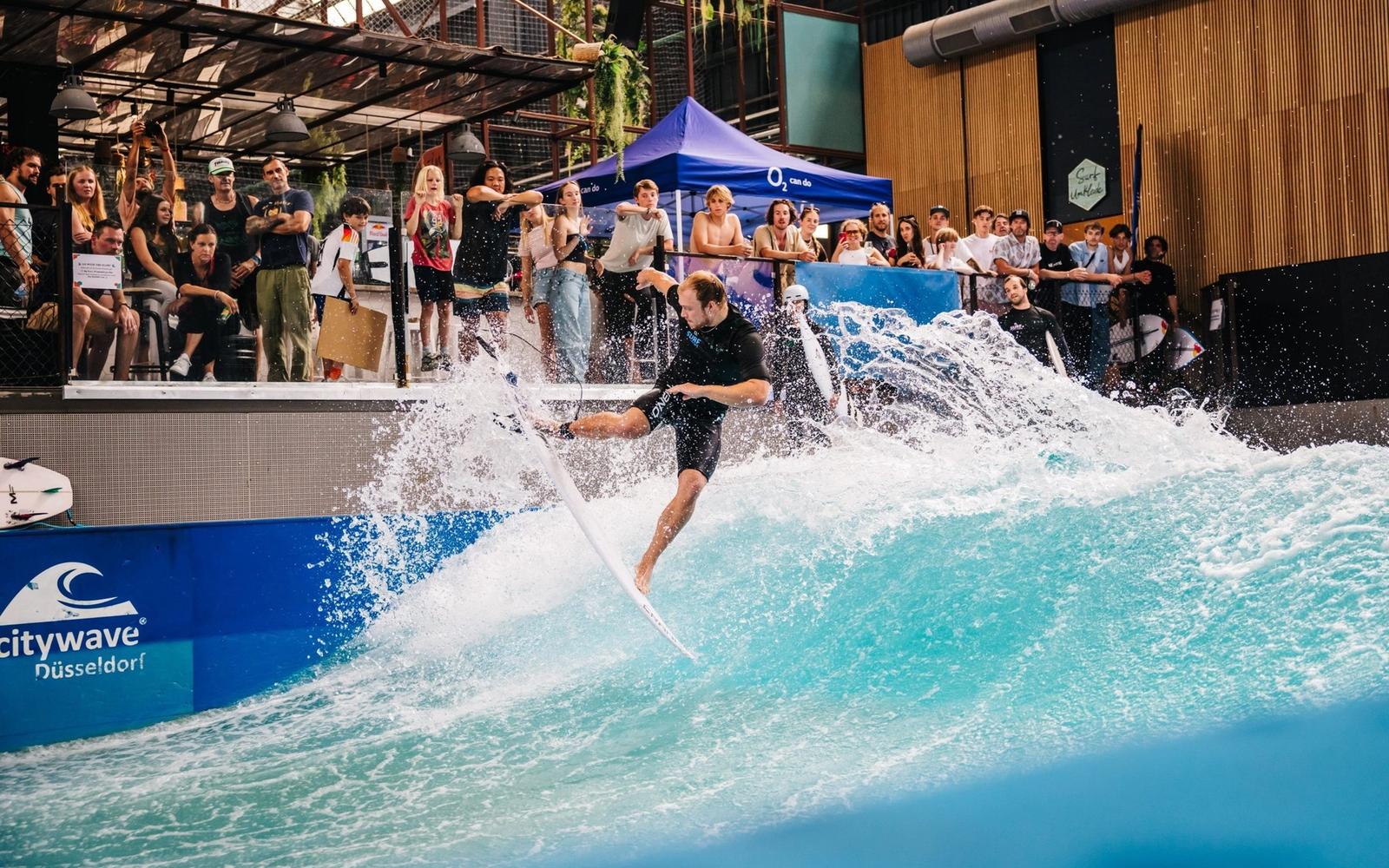 A surfer throws spray in front of a crowd at RheinRiff's indoor wave.