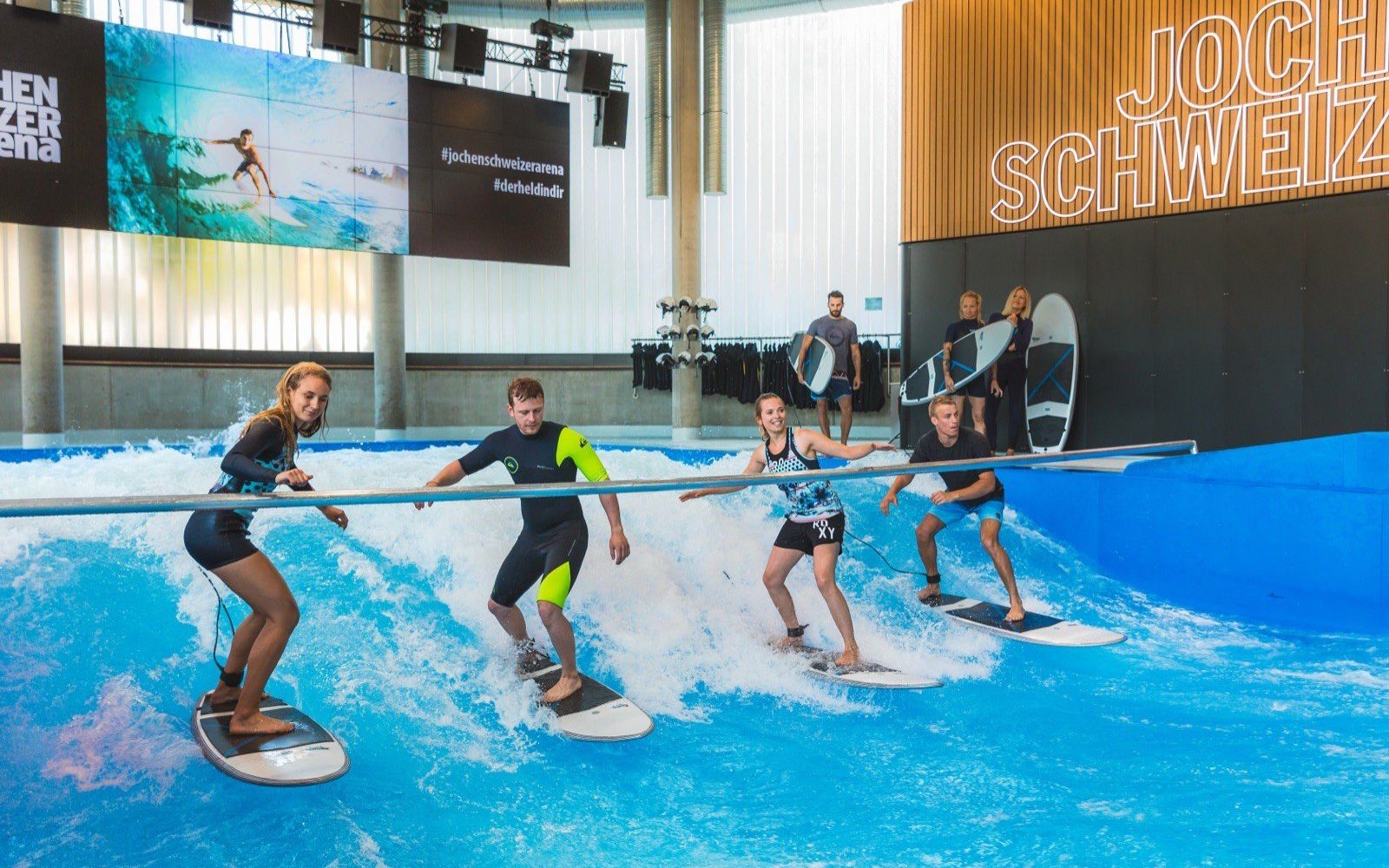 A beginner group holding the rail on the indoor wave at Jochen Schweizer Arena.