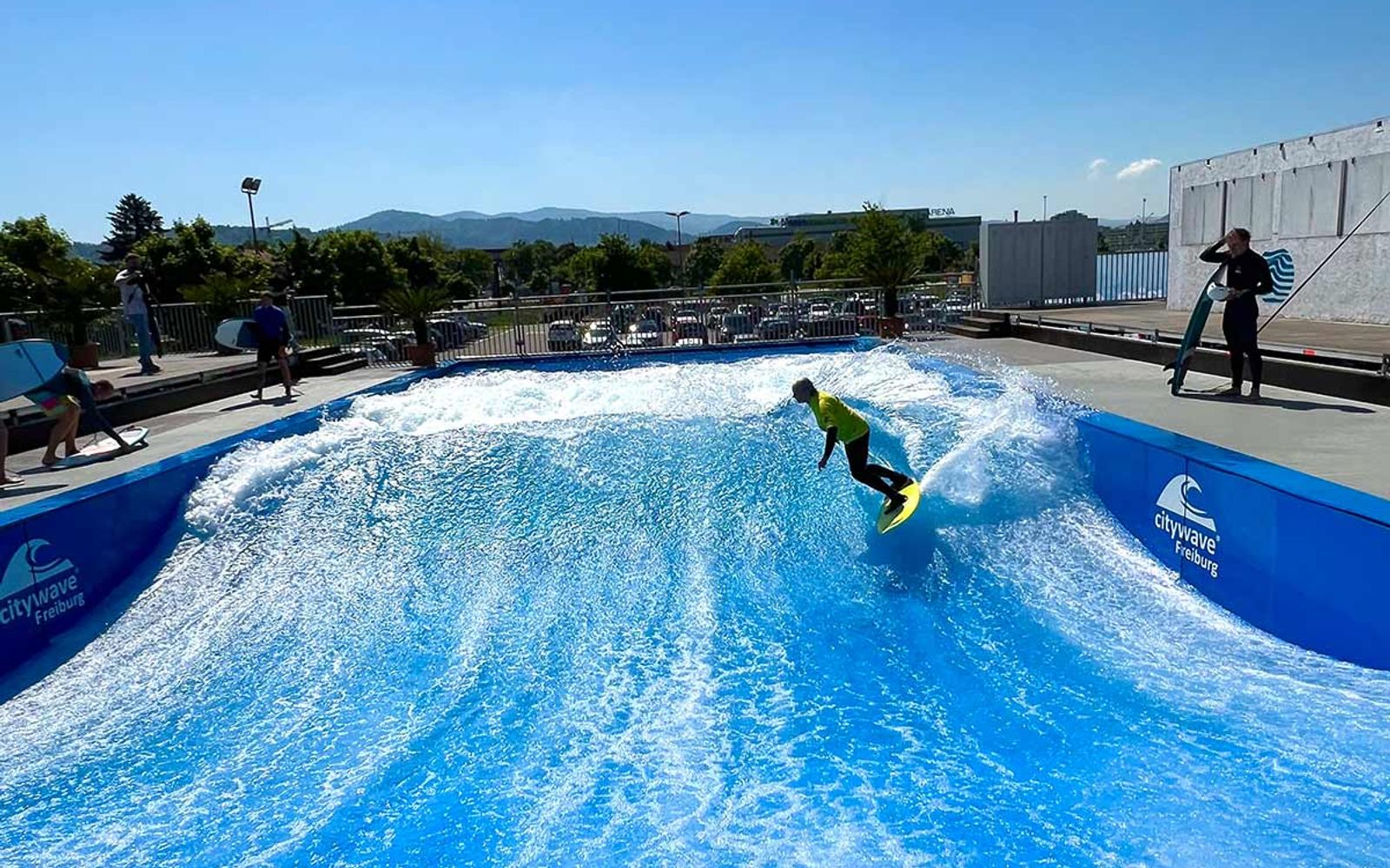 A surfer on irie surf's outdoor wave in Freiburg, with the Black Forest hills on the horizon.