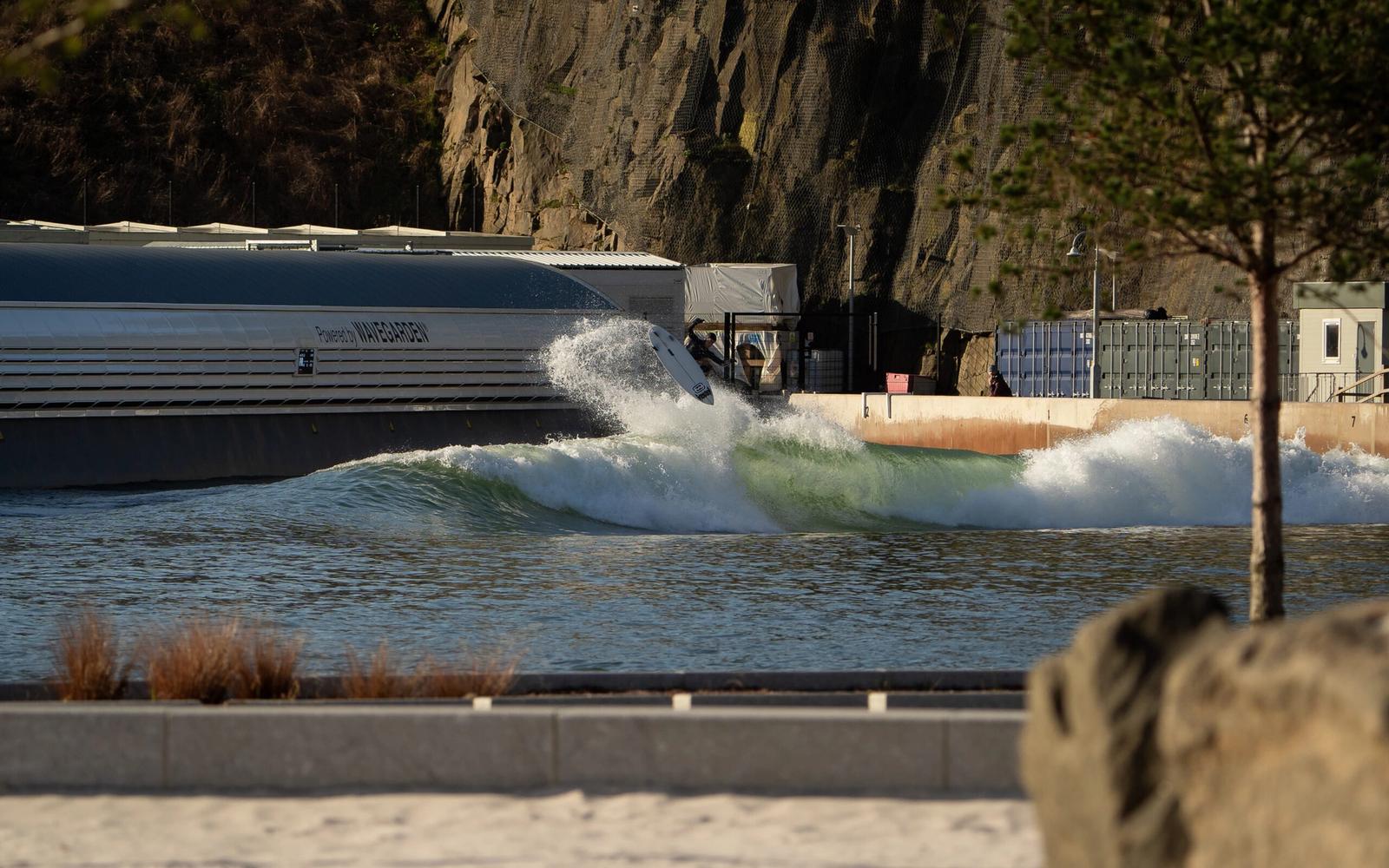 A surfer hits the lip beside the Wavegarden pier at Lost Shore, under the rock face of the old Craigpark quarry the resort was built in.