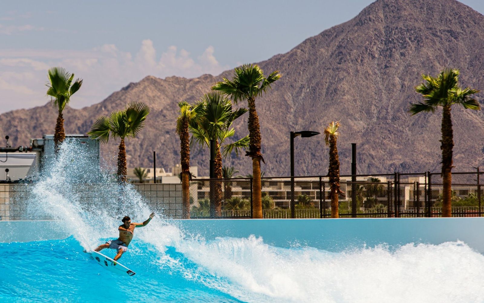 Griffin Colapinto on the wave at DSRT Surf, with palms and the desert mountains behind the lagoon.