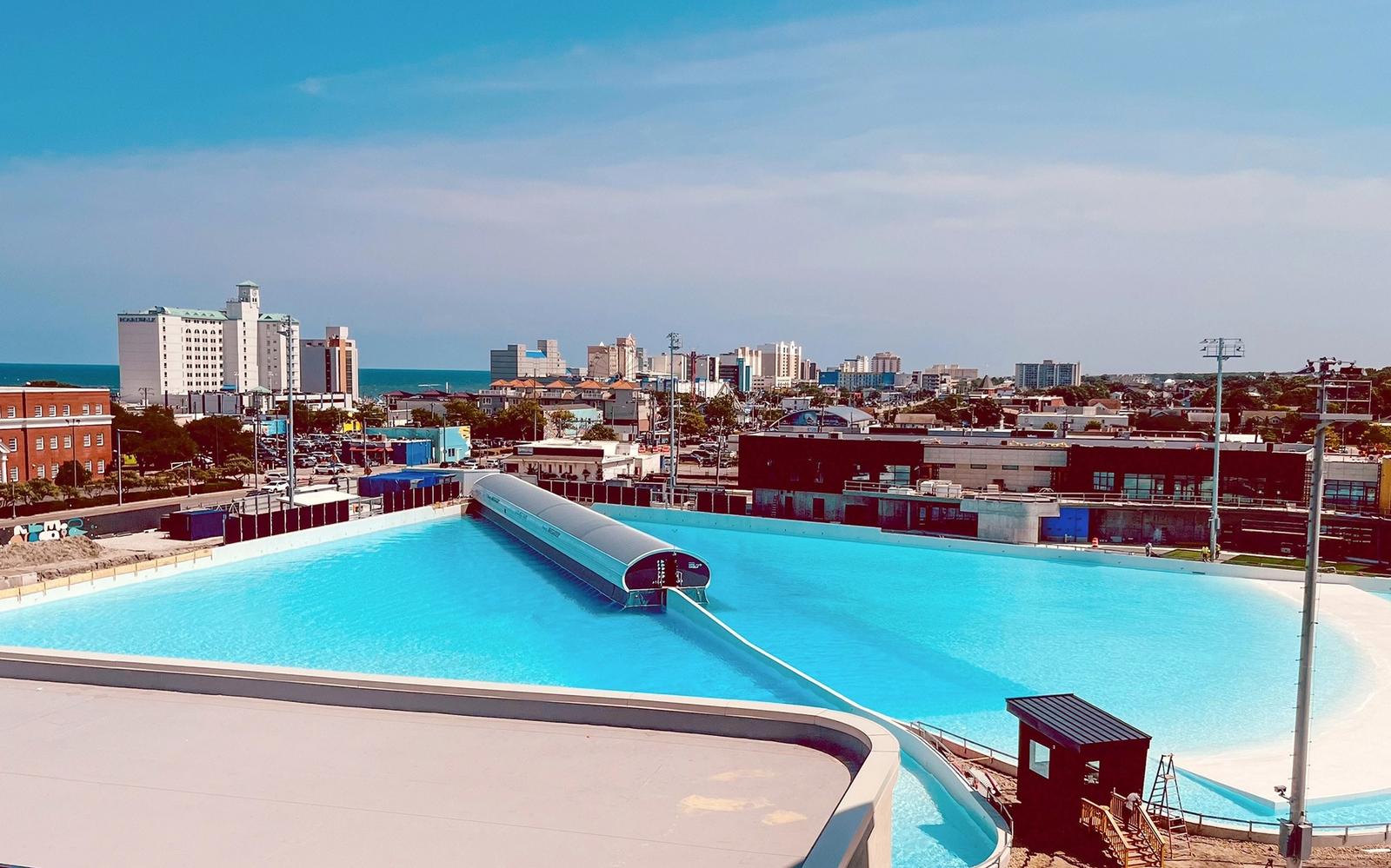 Atlantic Park's lagoon from above, with the Virginia Beach oceanfront hotels and the Atlantic behind.