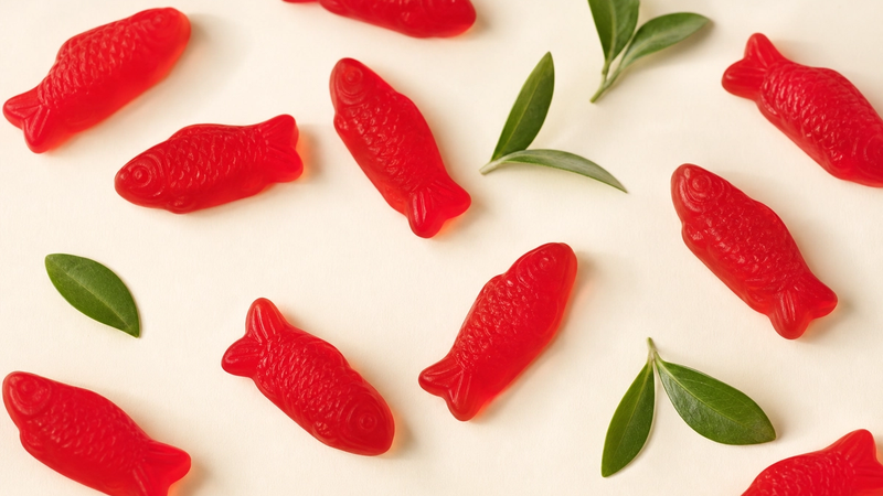 Red Swedish Fish candies with fresh leaves suggesting vegan candy