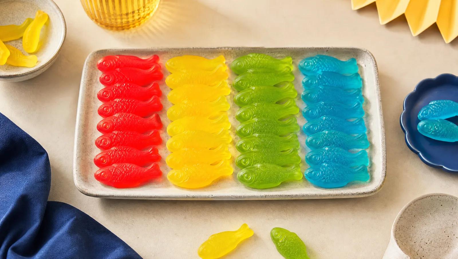 Fish-shaped gummies sorted into colour columns, red, yellow, green and blue, overhead.