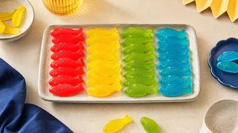 Fish-shaped gummies sorted into colour columns, red, yellow, green and blue, overhead.