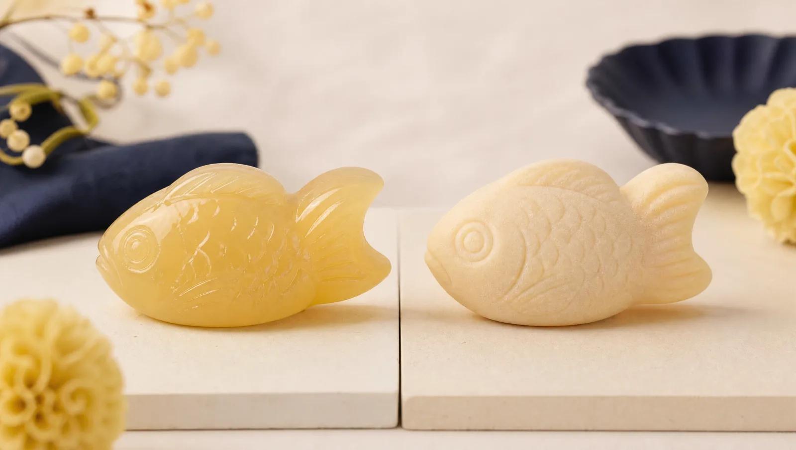 Two fish-shaped sweets side by side on a split cream surface, one glossy one matte, comparison framing.