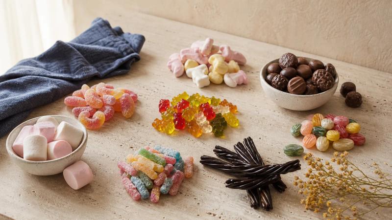 An overhead spread of many candy types arranged in small clusters on a pale stone surface.