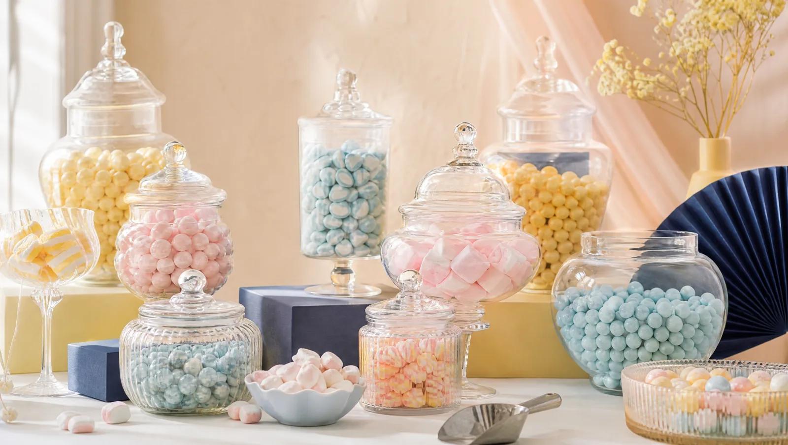 Colour-themed candy buffet in soft pastels with varied jar heights and a scoop.