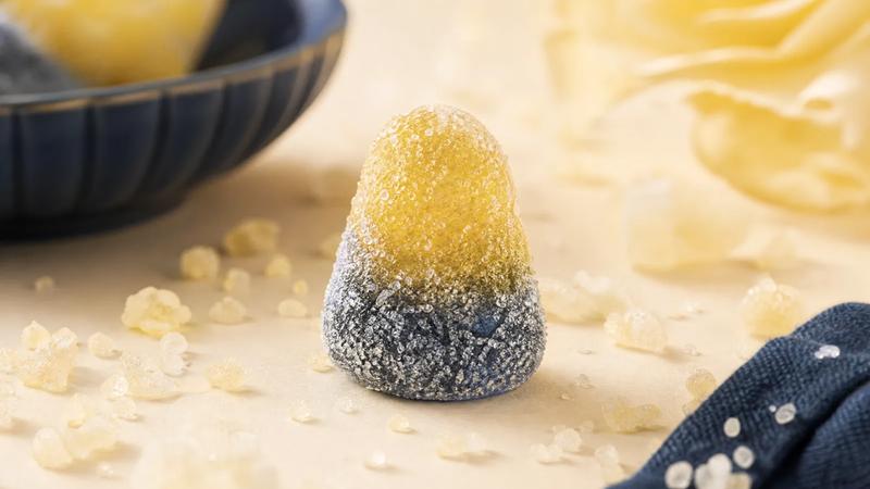 A single intensely coated sour sweet with a scatter of acid crystals.