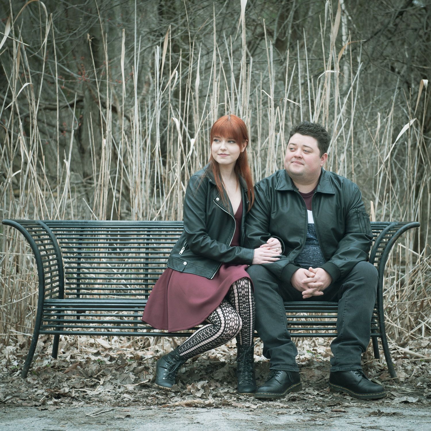 A couple sitting together on a green park bench in late autumn