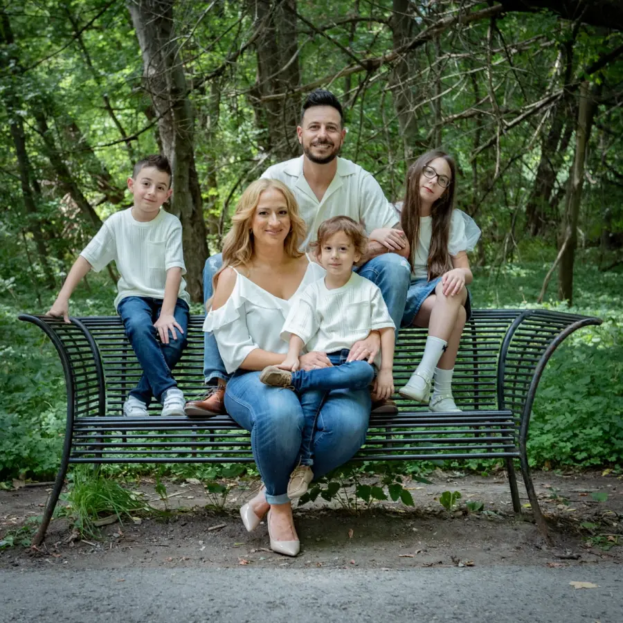 Sara & Rocco's family grouped on and around a green park bench