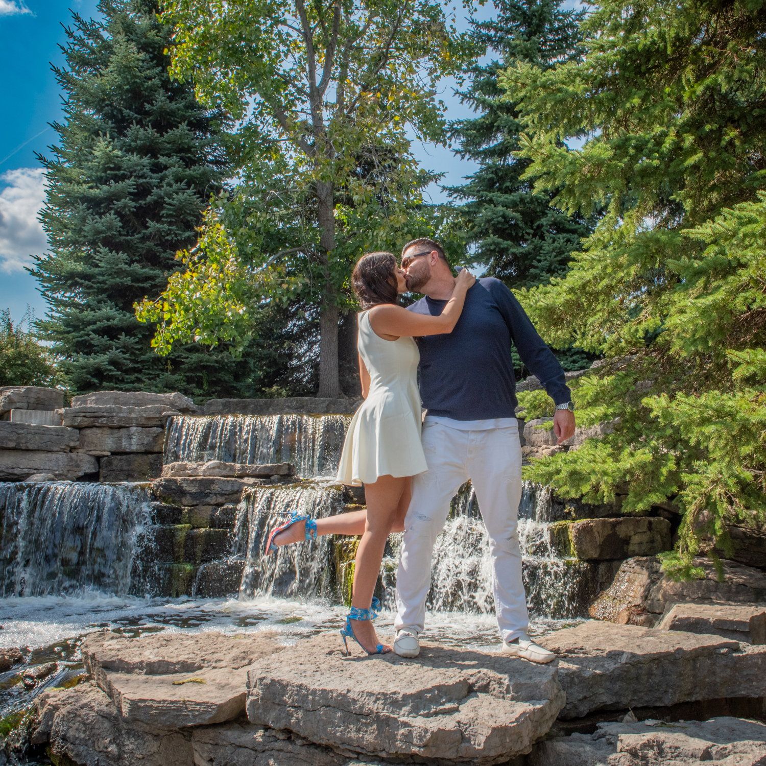 Marina & Eric kissing on the rocks beside a garden waterfall