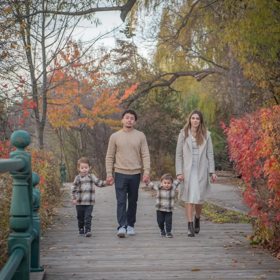 Melanie & Harold walking a boardwalk with their sons past red autumn shrubs