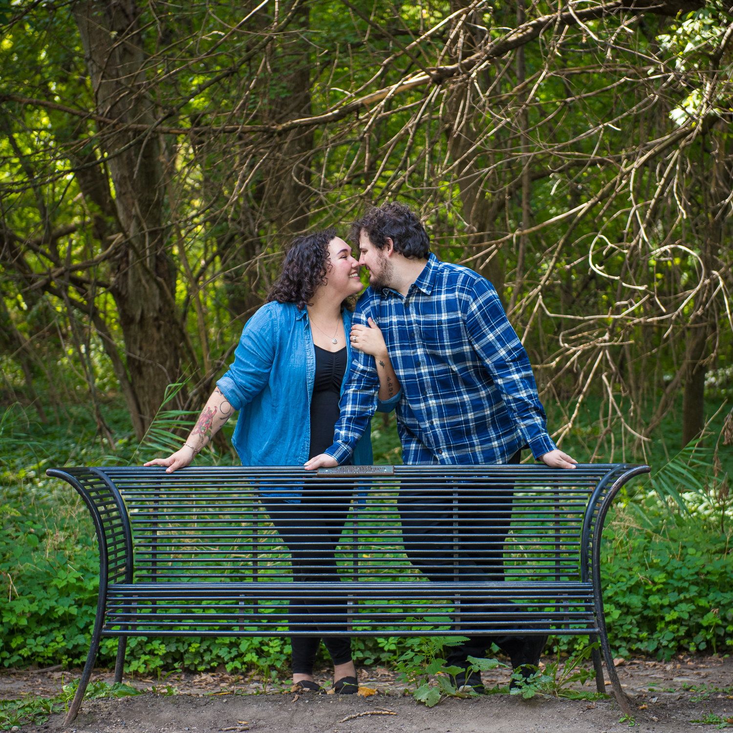 A couple leaning together over a park bench under new spring growth