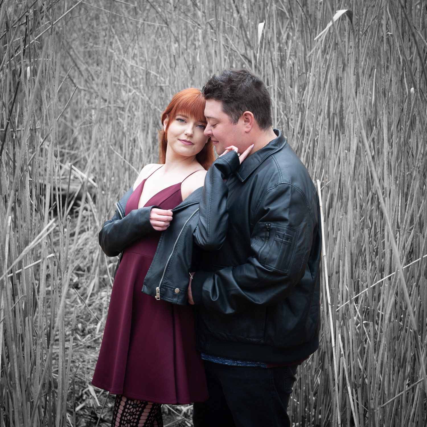 Black-and-white photo of a couple holding each other in tall winter reeds