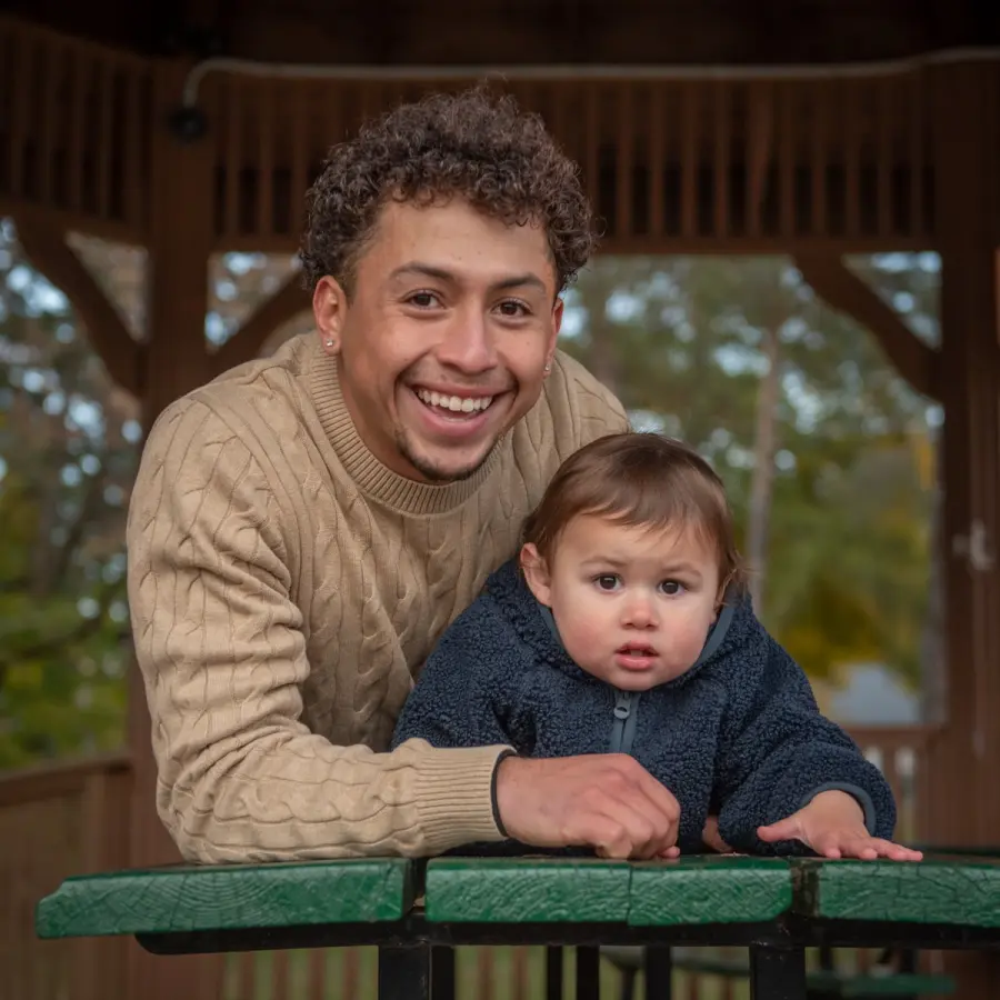 Harold holding his youngest at a gazebo railing, both smiling at the camera