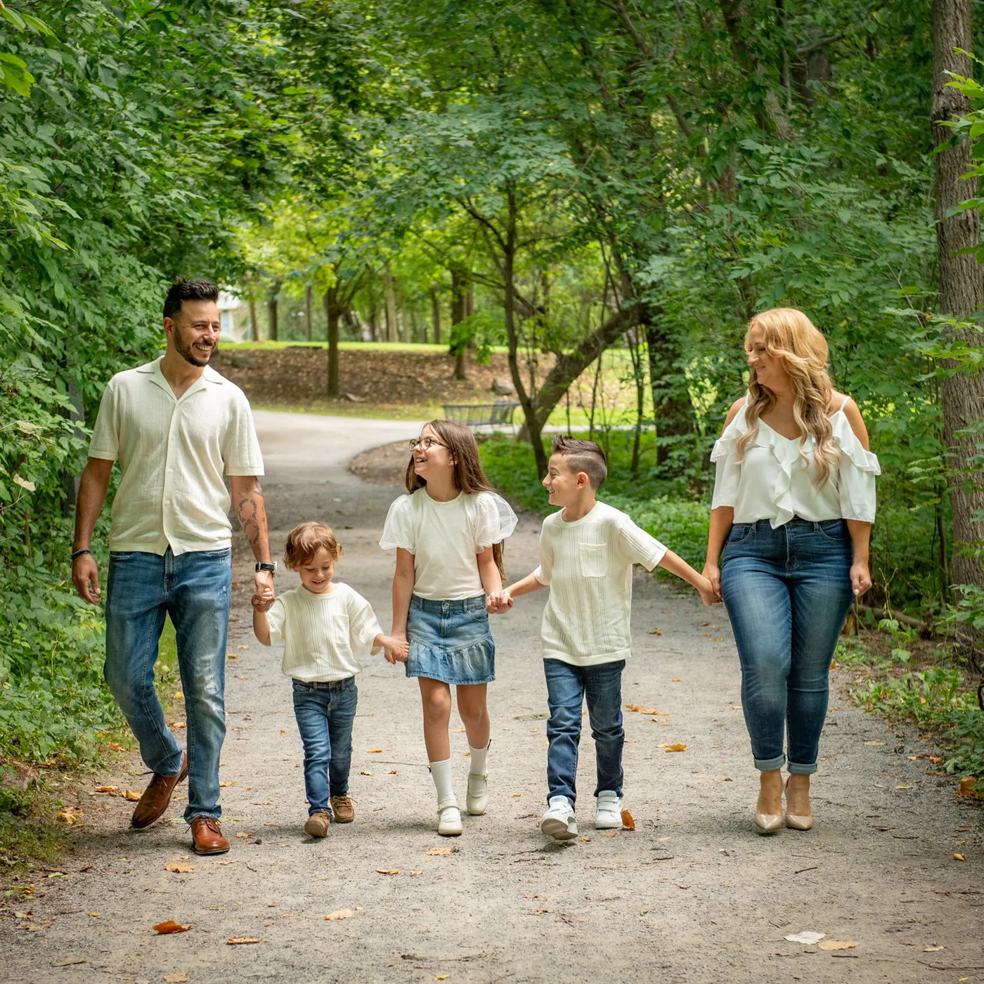 Sara & Rocco and their children walking hand in hand down a gravel path