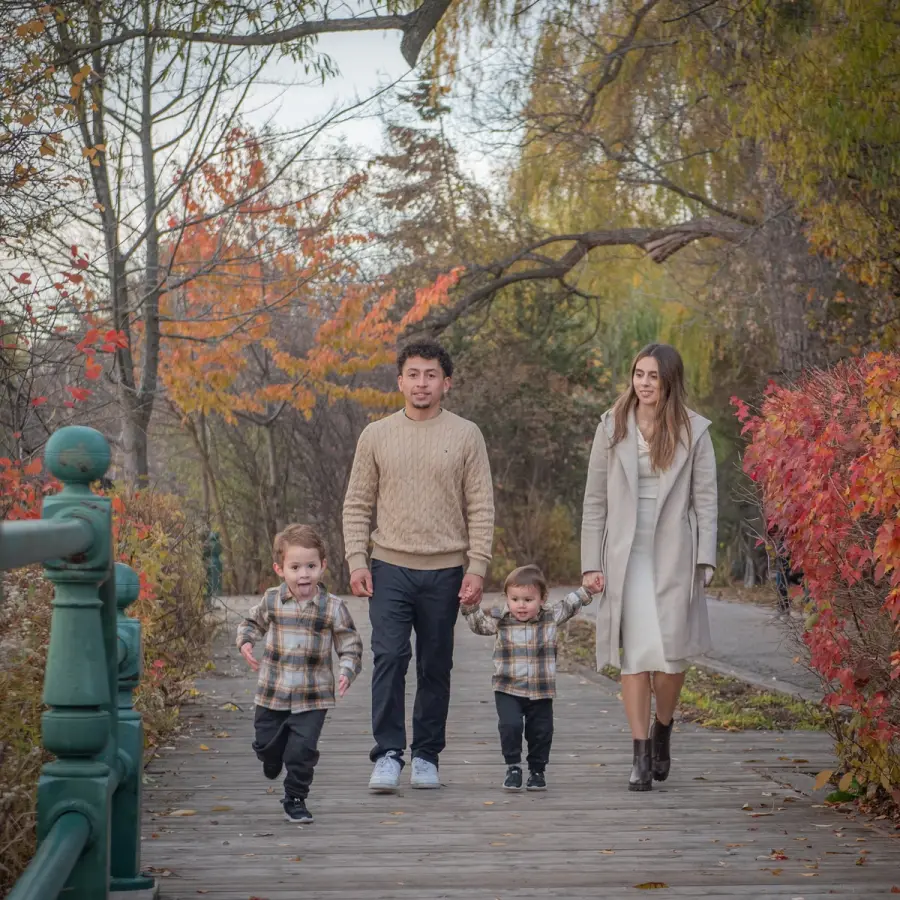 Melanie & Harold's family walking a wooden bridge in full autumn colour