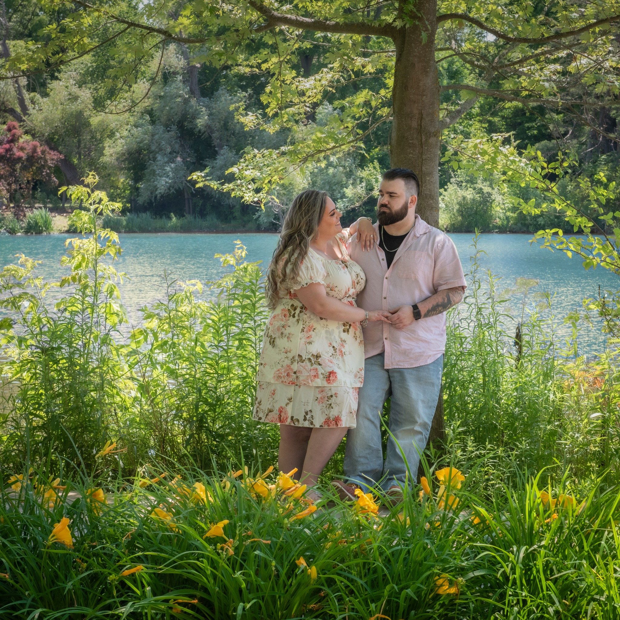 A couple laughing together among orange day lilies at the edge of a pond