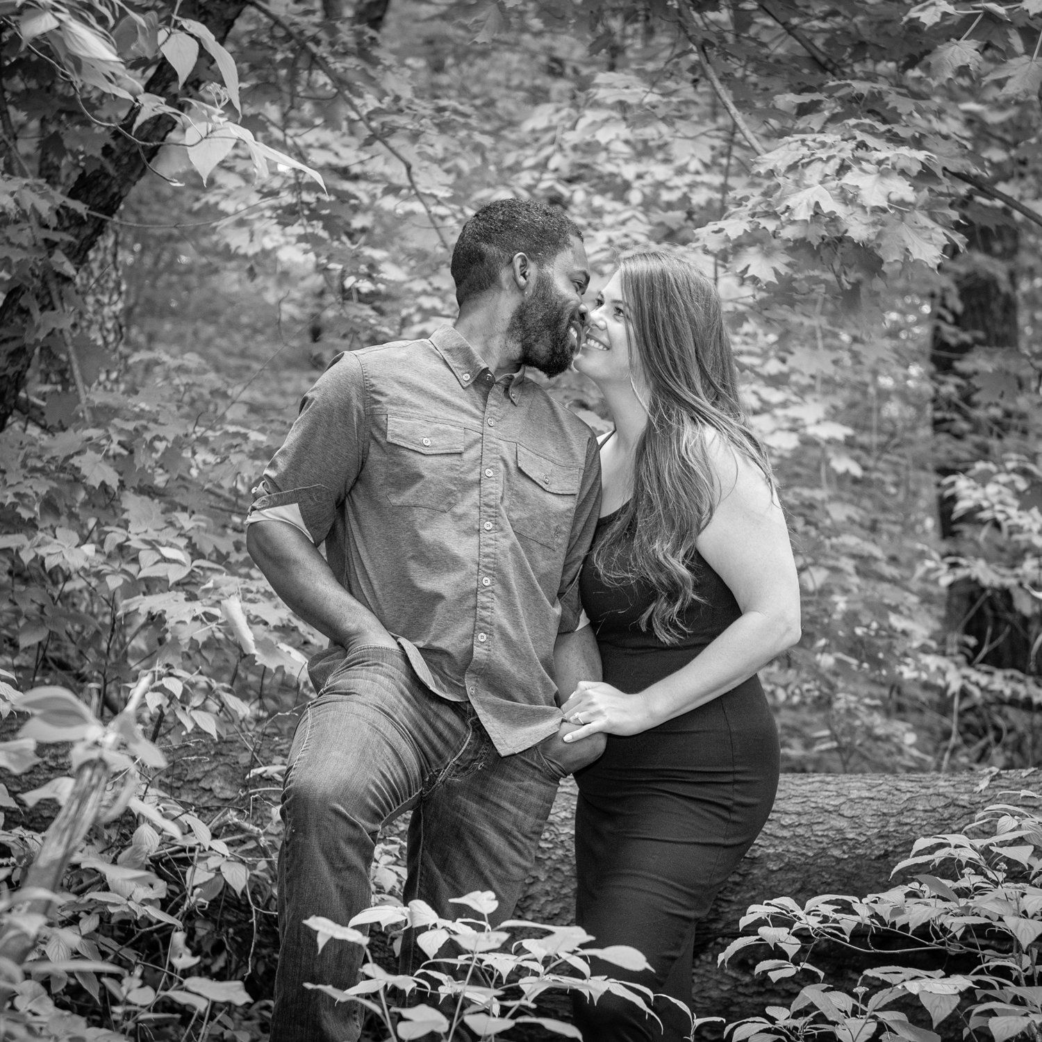 Black-and-white photo of a couple about to kiss beside a stone wall