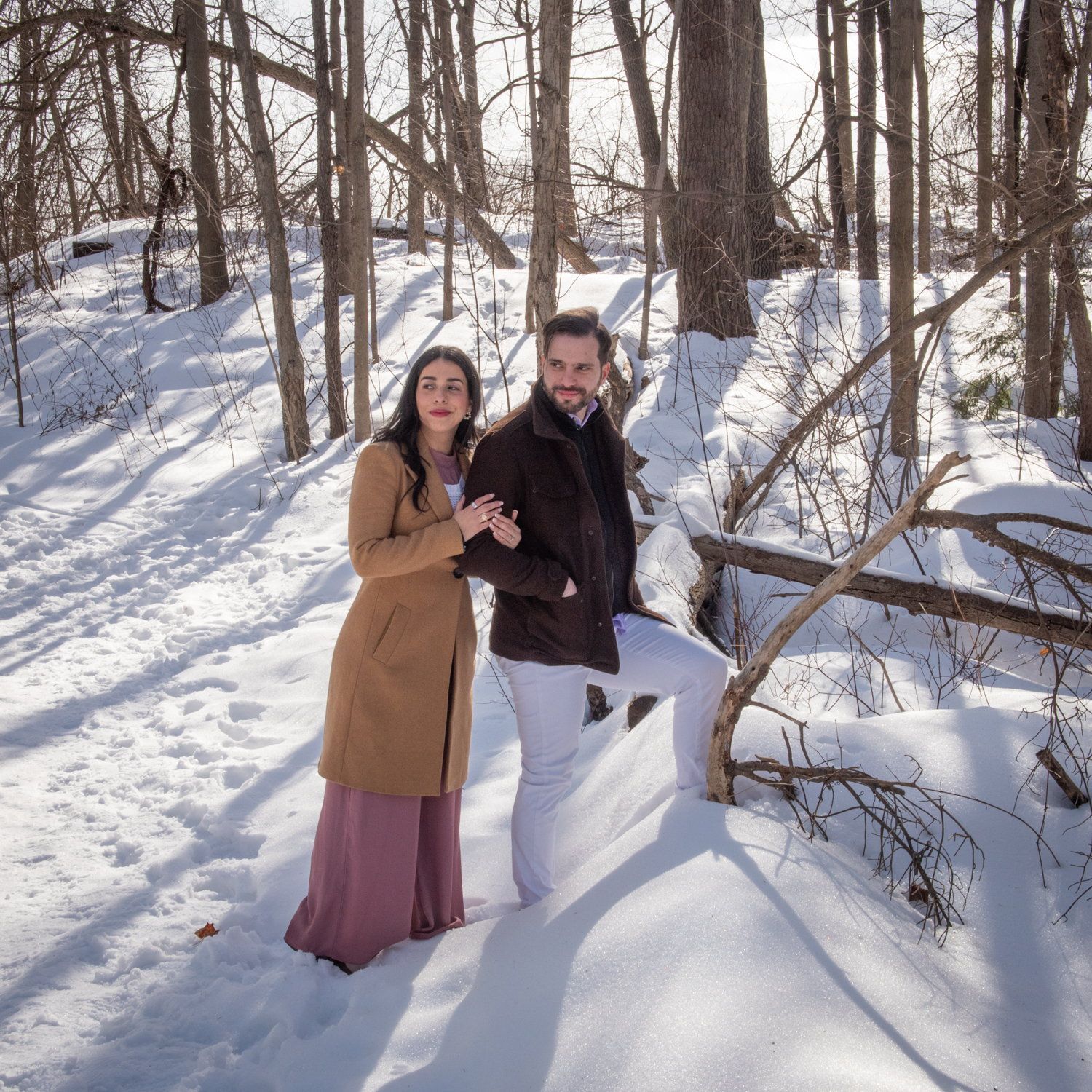 Kisa & Larry standing together in a snowy wood, bare trees behind them
