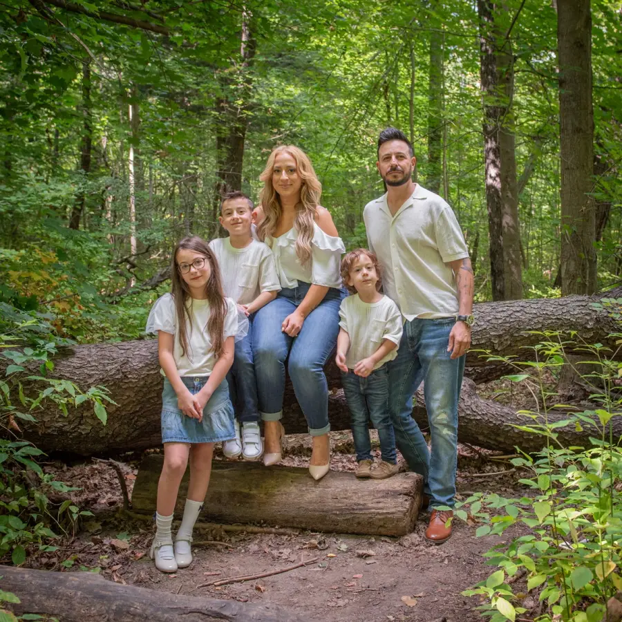 Sara & Rocco seated on a fallen log with their children on either side