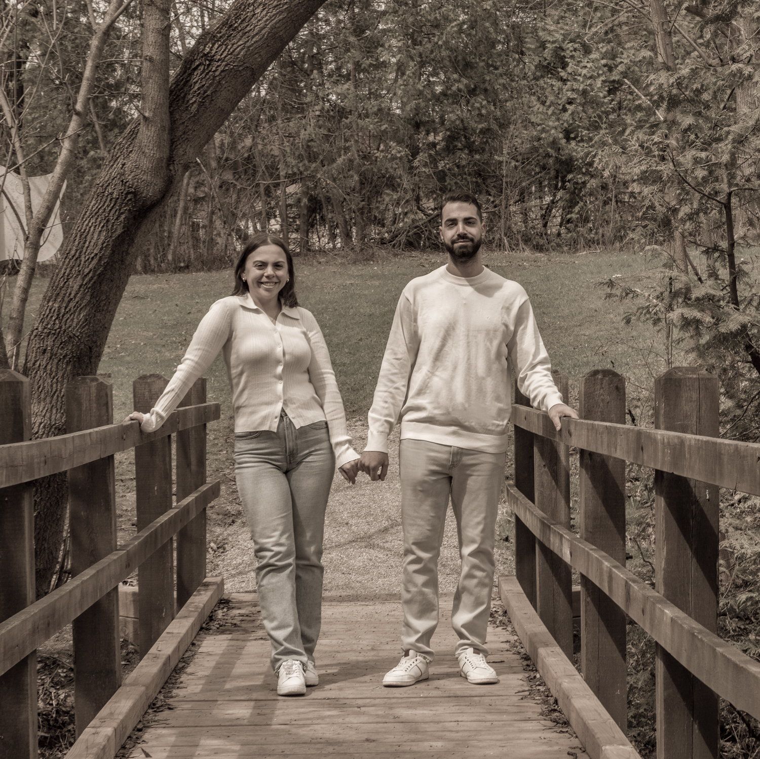 Black-and-white photo of a couple walking a wooden boardwalk hand in hand
