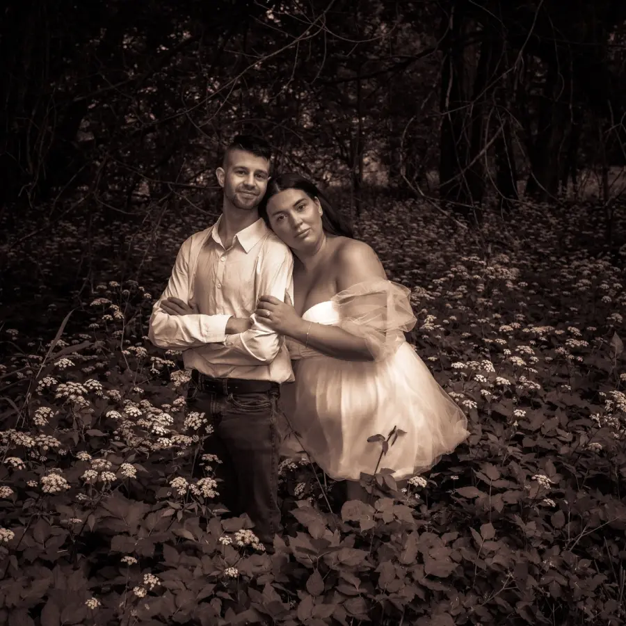 Warm-toned photo of a couple kneeling together in deep fallen leaves