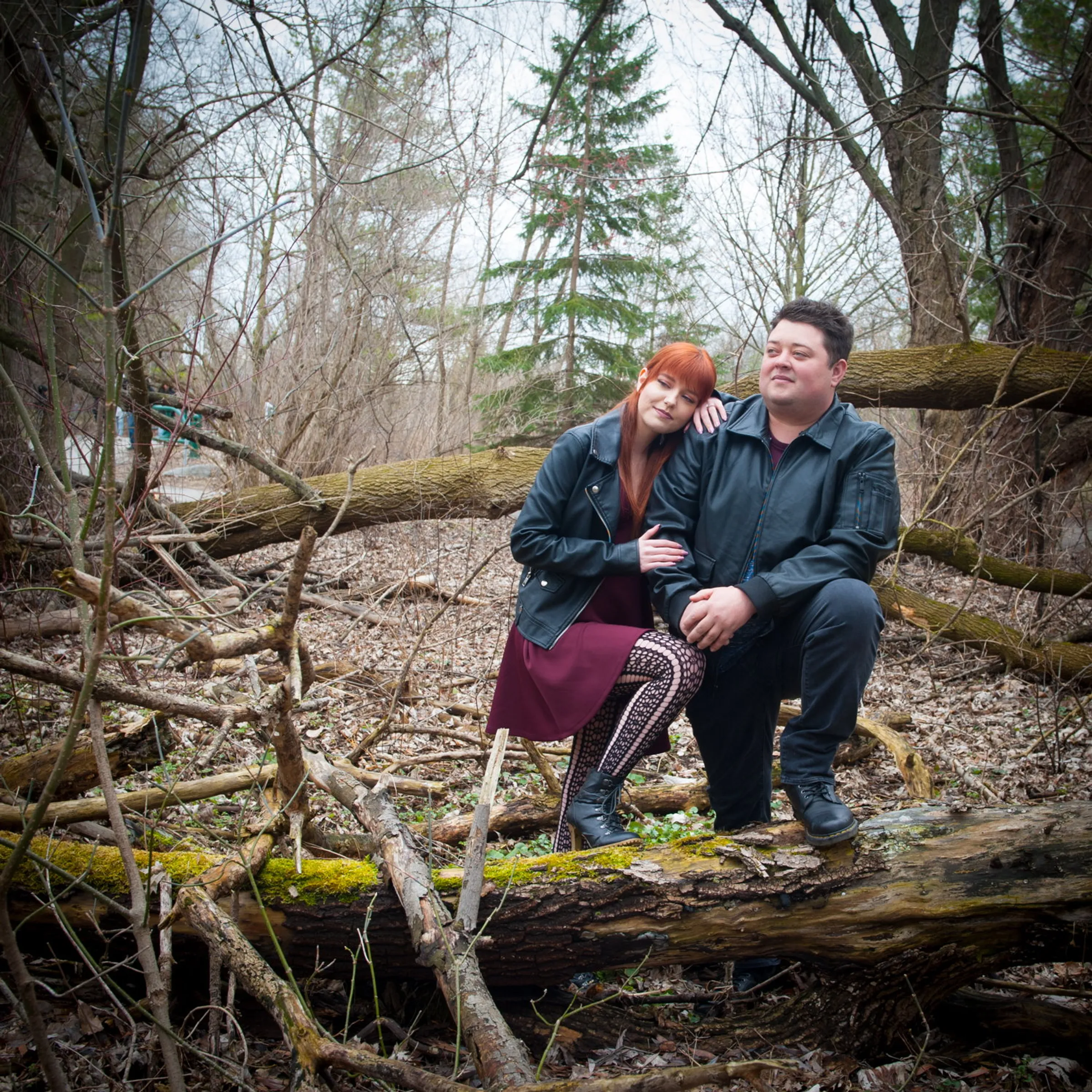 A couple resting on a fallen log over a creek in early spring