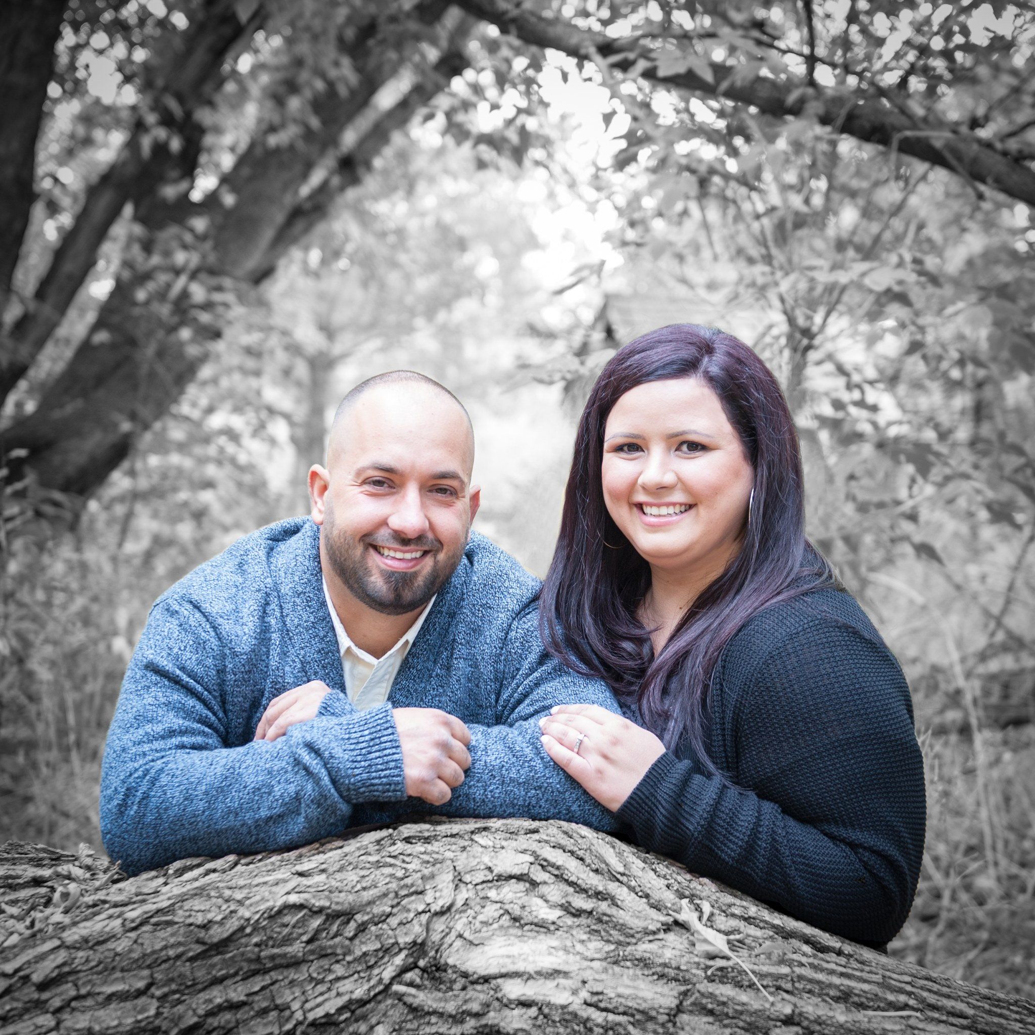 A couple leaning on a fallen log at Mill Pond, the background in black and white