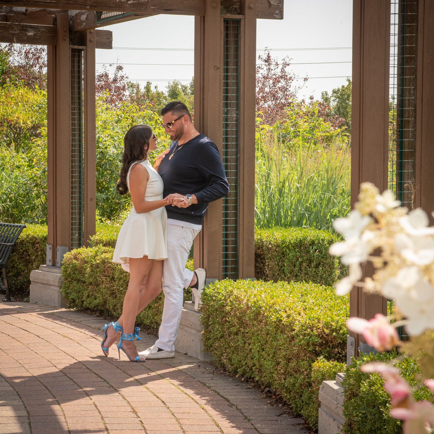 Marina & Eric under a garden pergola, her in a white dress