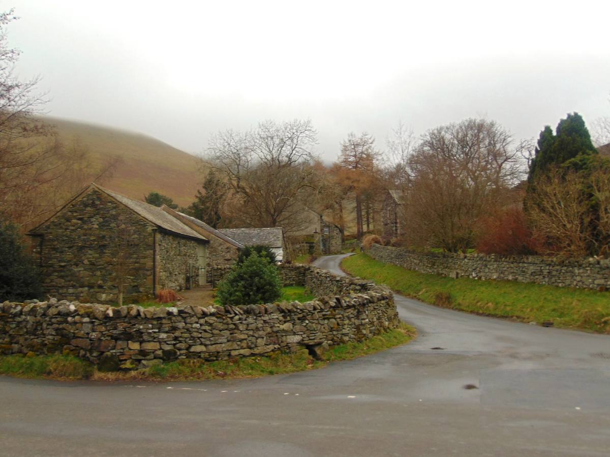 An old stone barn beside a walled lane with the fellside lost in mist behind