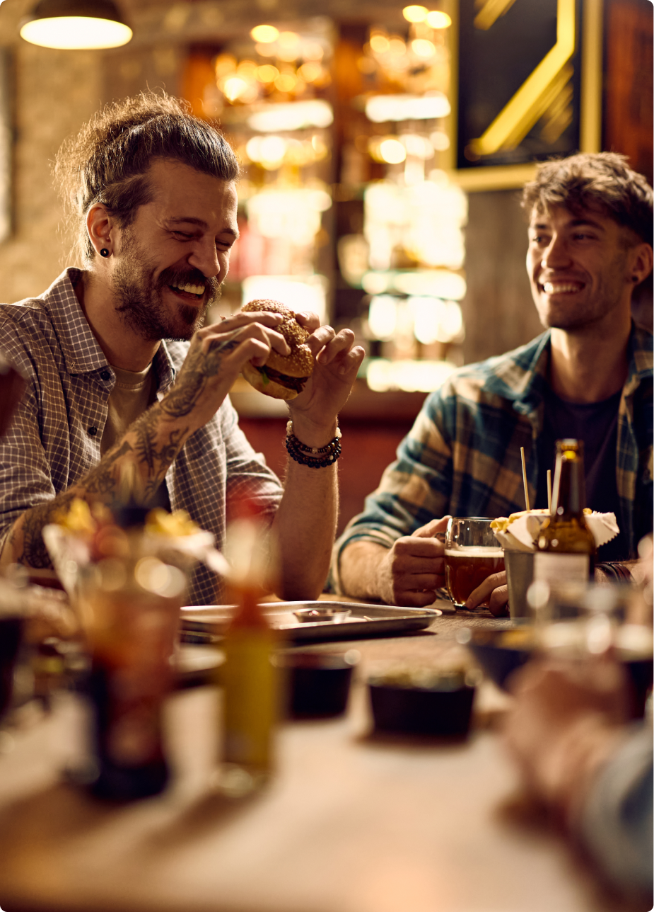 Friends around a pub table with burgers and drinks, laughing together
