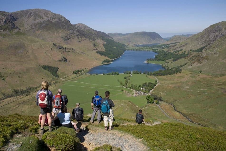 A group of walkers resting on the path high above Buttermere and its valley