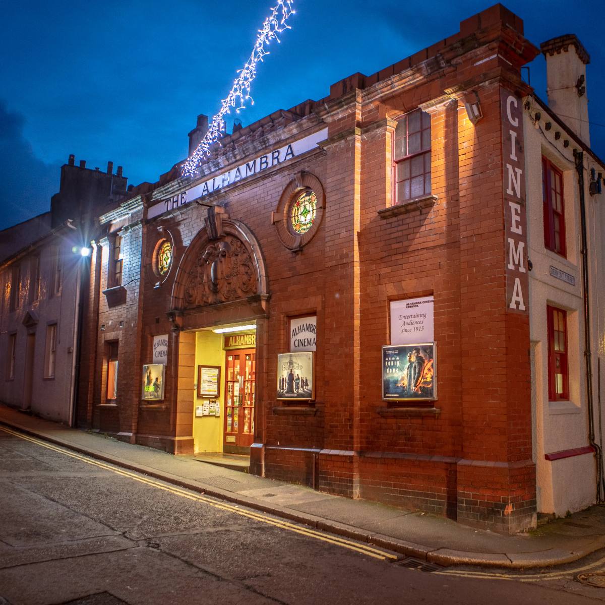 The lit frontage of the Alhambra Cinema in Keswick at dusk