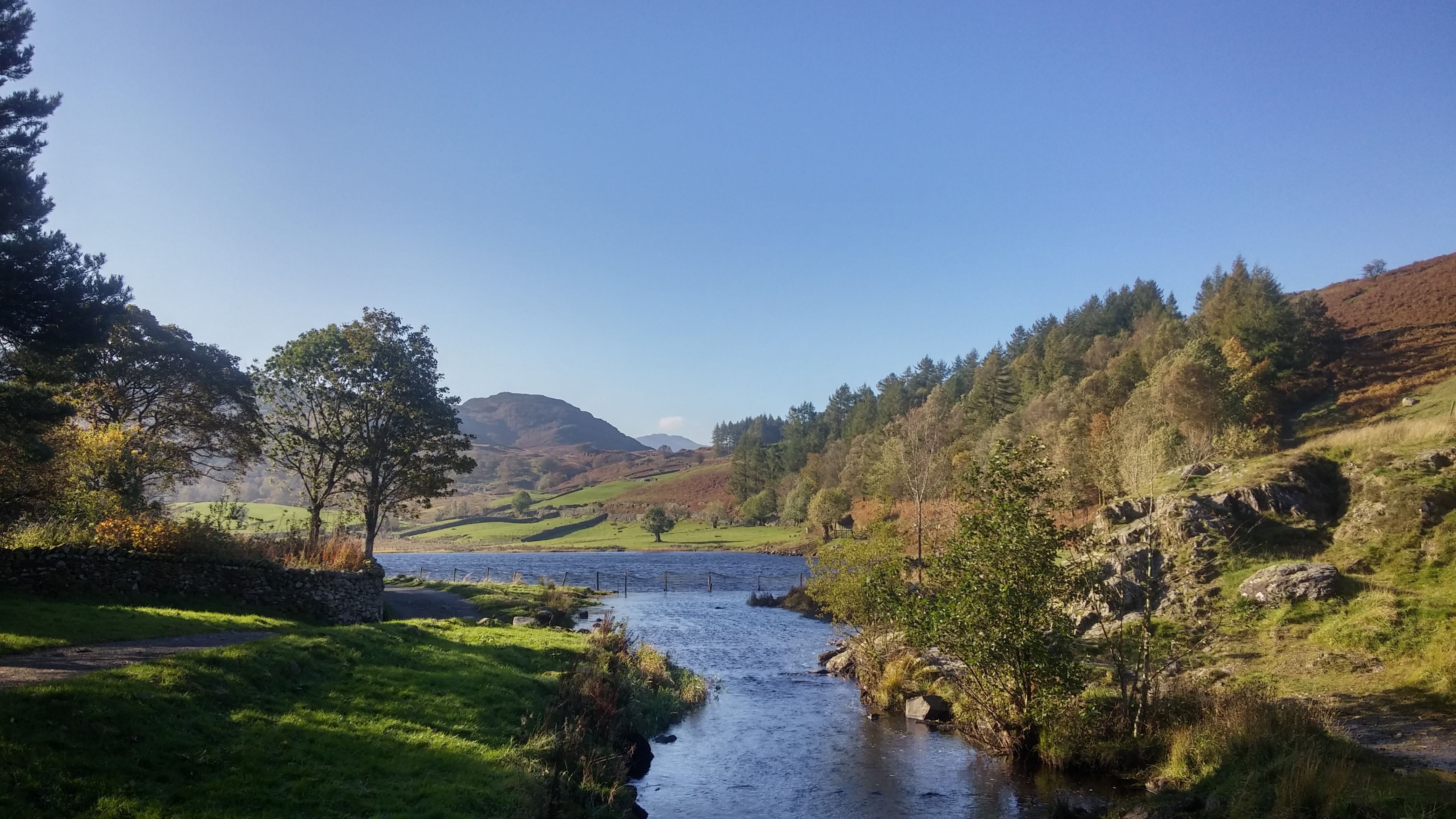 A beck running over rocks below Ashness Bridge with Derwentwater beyond