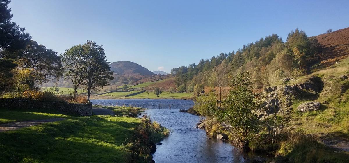 A beck running over rocks below Ashness Bridge with Derwentwater beyond