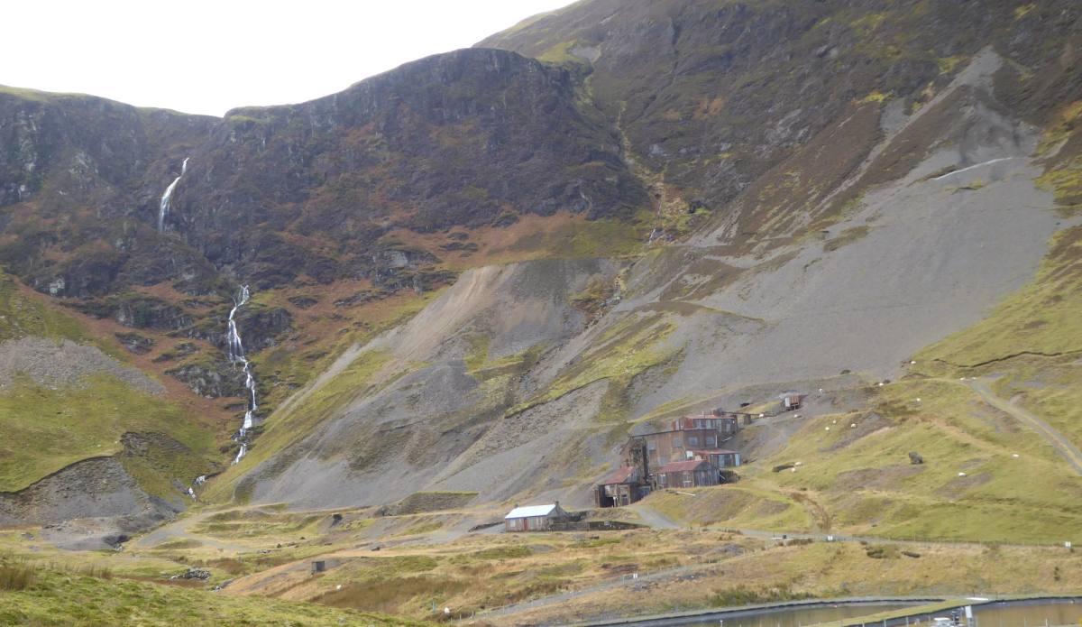 The white buildings of Force Crag mine below a waterfall falling down the crag