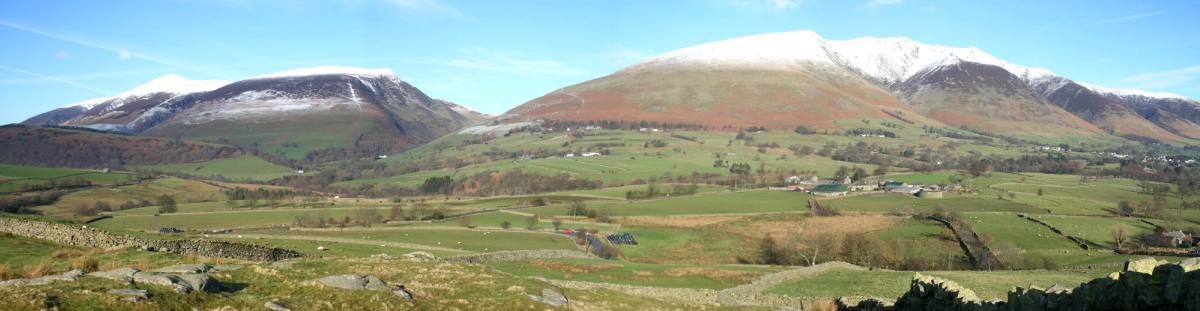 The long ridge of Skiddaw and Blencathra rising over farmland with snow on the tops