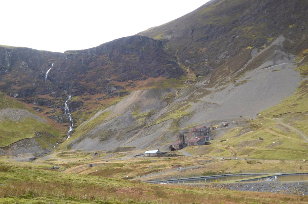 A thin waterfall falling down the bare scree slopes of a high fell