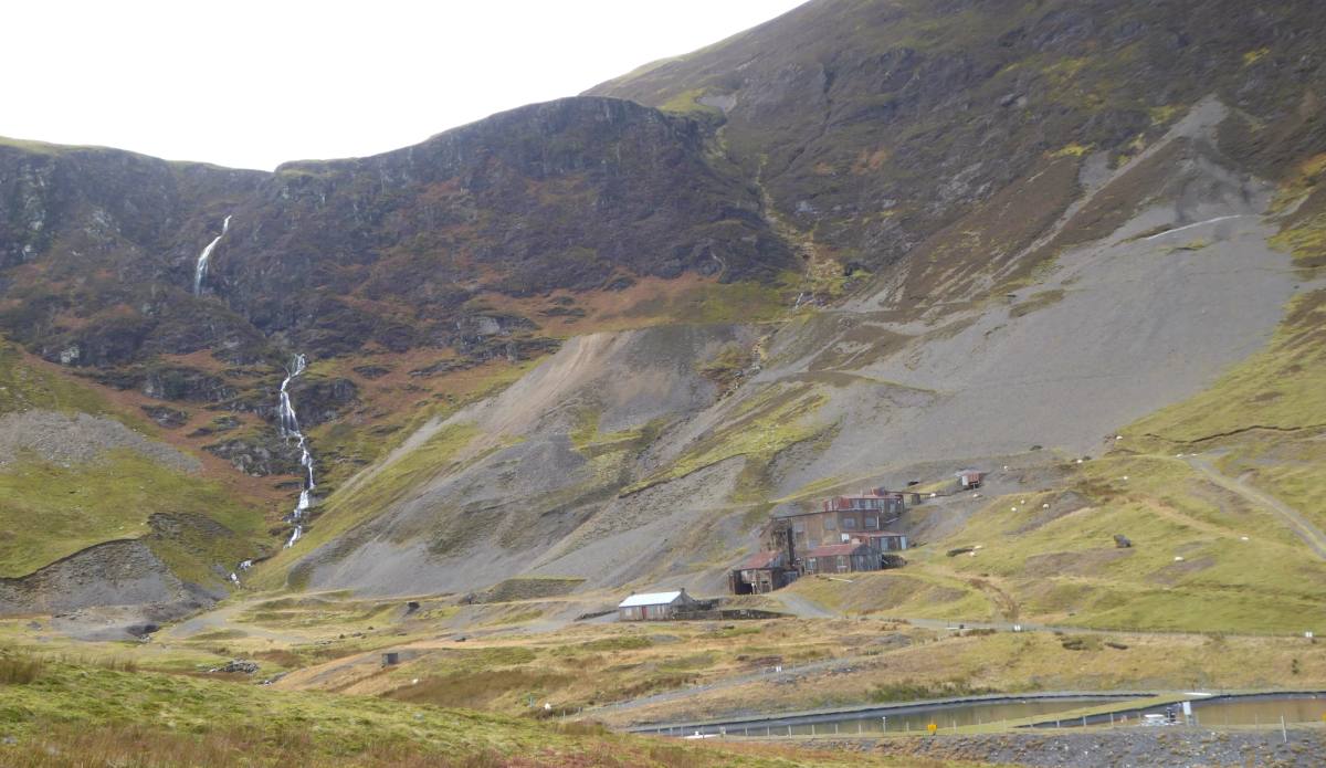 A thin waterfall falling down the bare scree slopes of a high fell