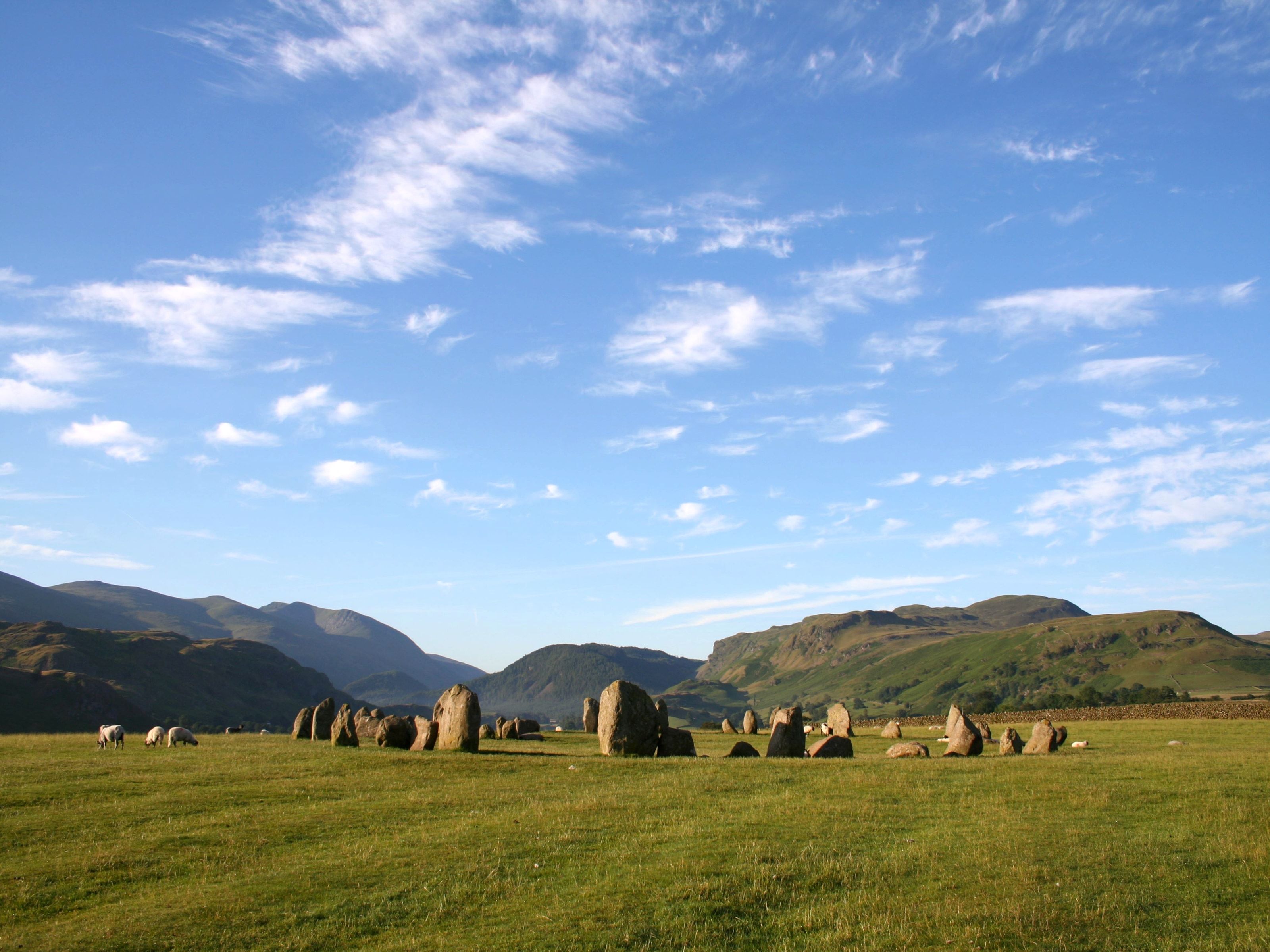 The Castlerigg stone circle on open grass under a wide sky of scattered cloud
