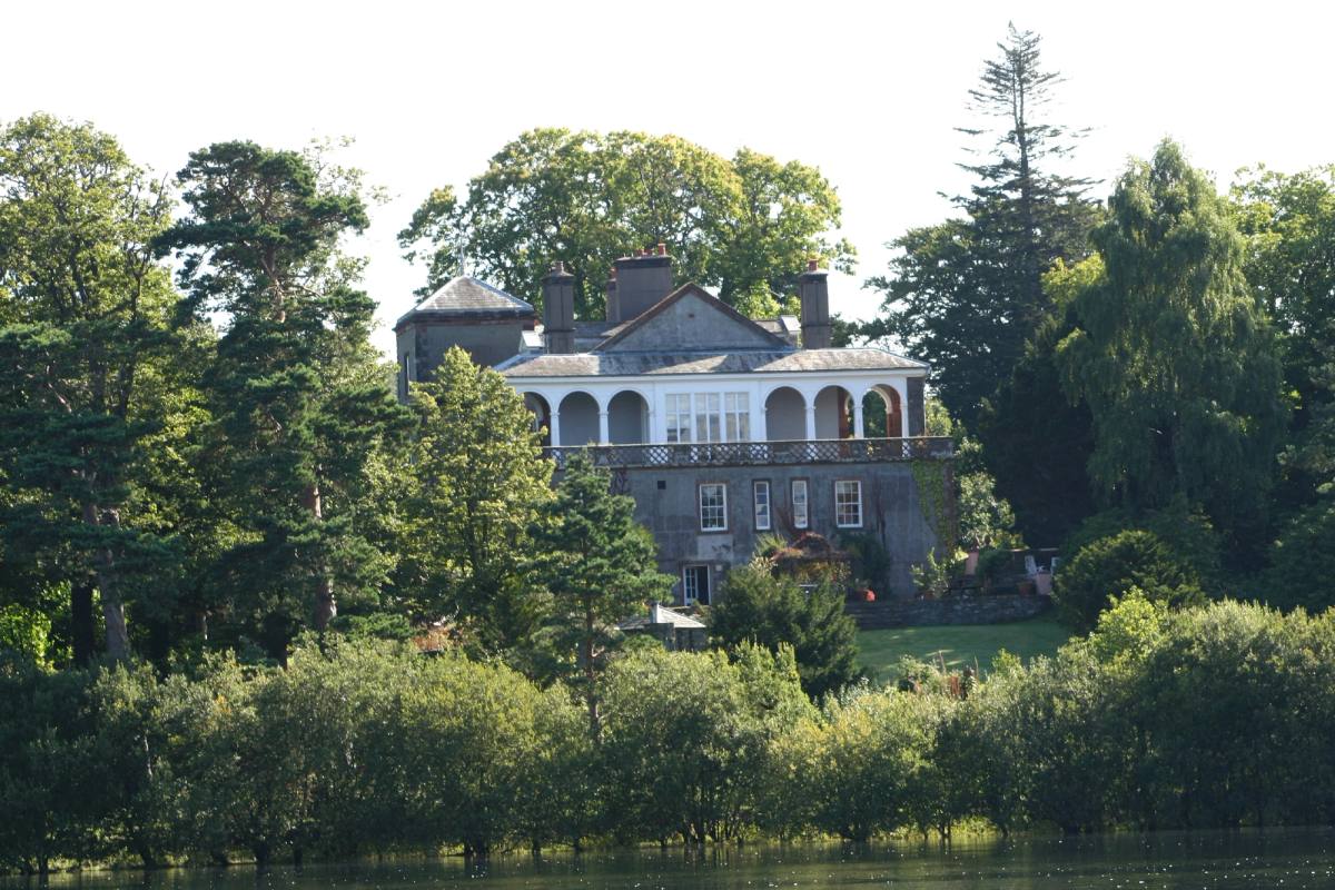 A white Georgian house on Derwent Isle glimpsed through tall trees