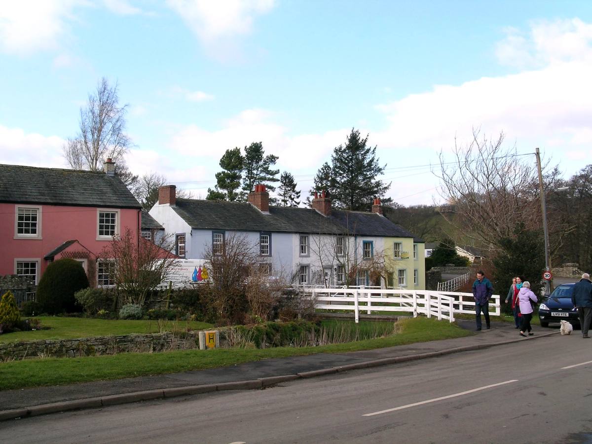 A row of village cottages with one washed pink beside the road at Ireby