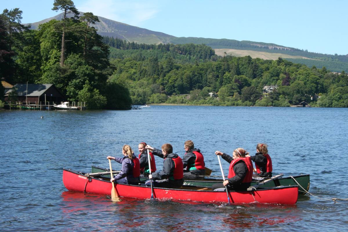 Kayakers paddling past one of the wooded islands on Derwentwater