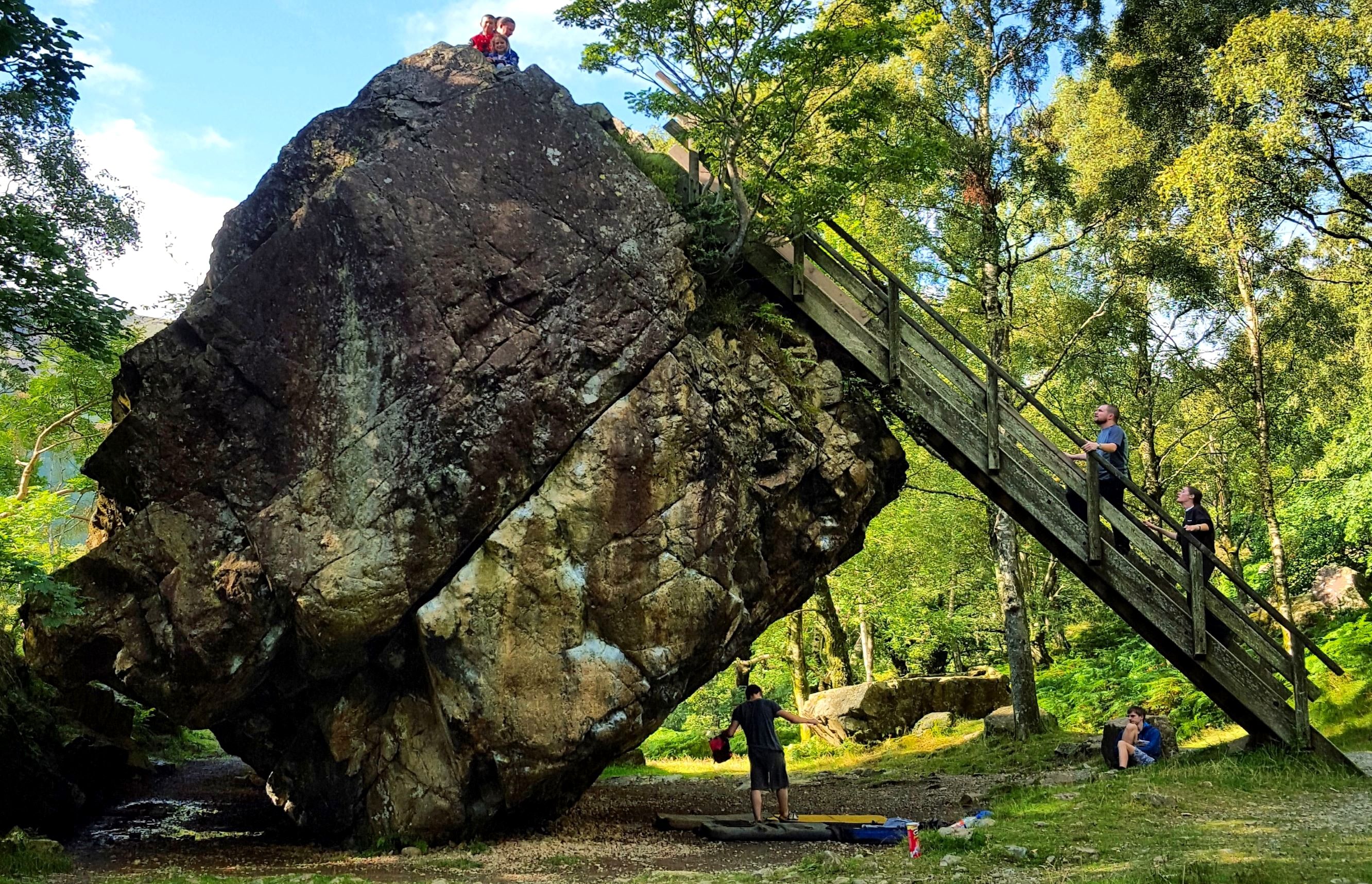 The Bowder Stone balanced on its edge with a wooden ladder leaning against it