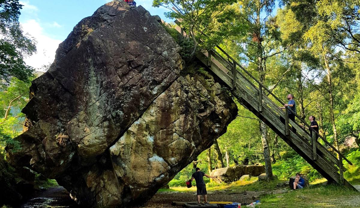 The Bowder Stone balanced on its edge with a wooden ladder leaning against it
