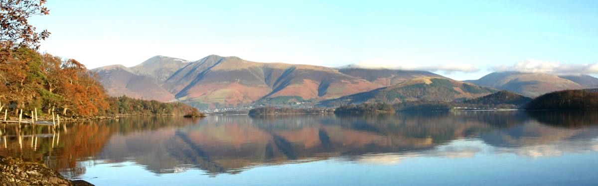 Derwentwater with autumn colour on the shoreline trees and the fells reflected